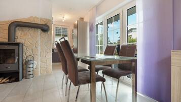 Een moderne keuken met een stenen muur, een inbouwfornuis en een eethoek met een glazen tafel en lederen stoelen.