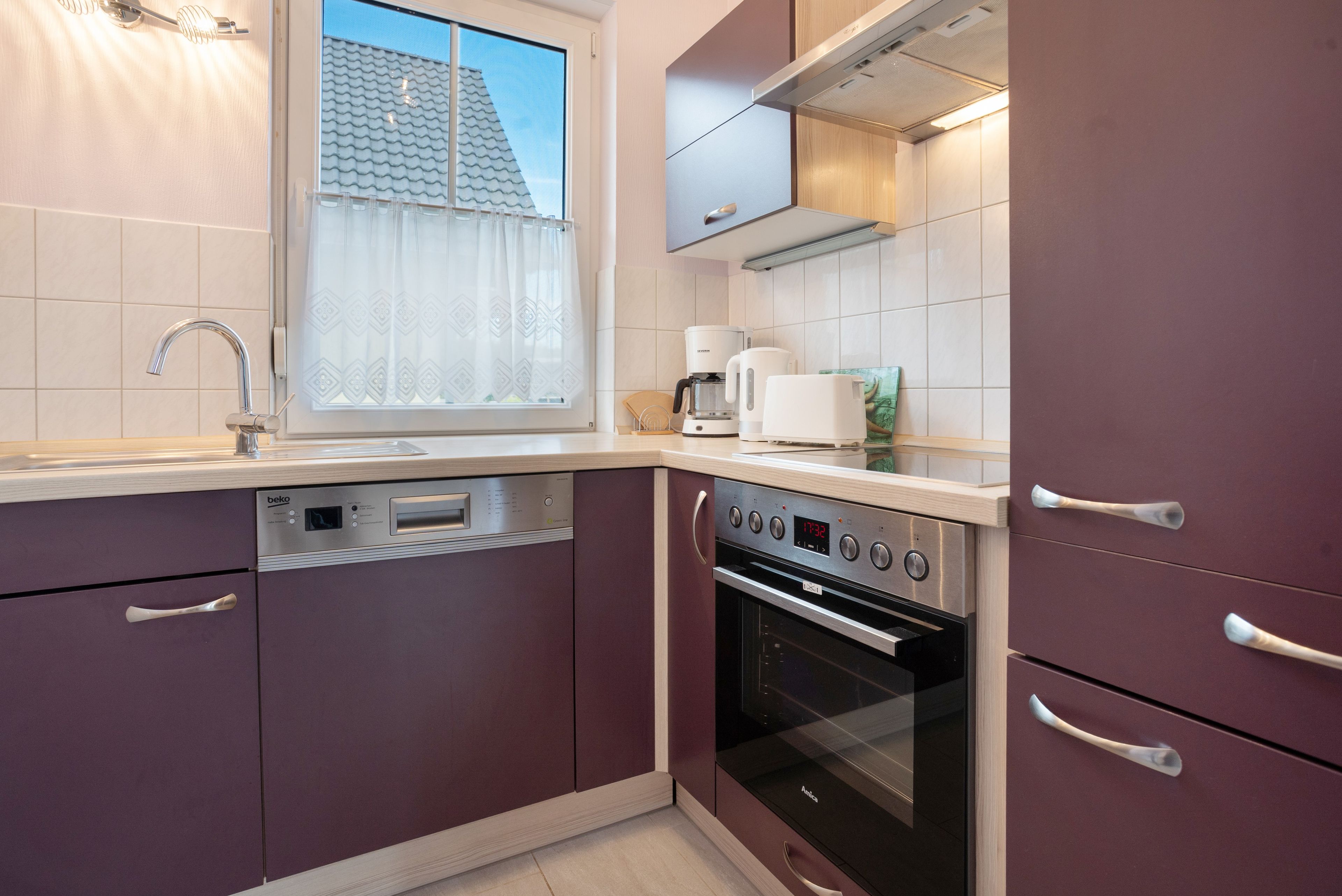 Een moderne keuken met ingebouwde apparatuur, een raam met uitzicht op het dak en een vaatwasser.