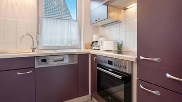 Een moderne keuken met ingebouwde apparatuur, een raam met uitzicht op het dak en een vaatwasser.