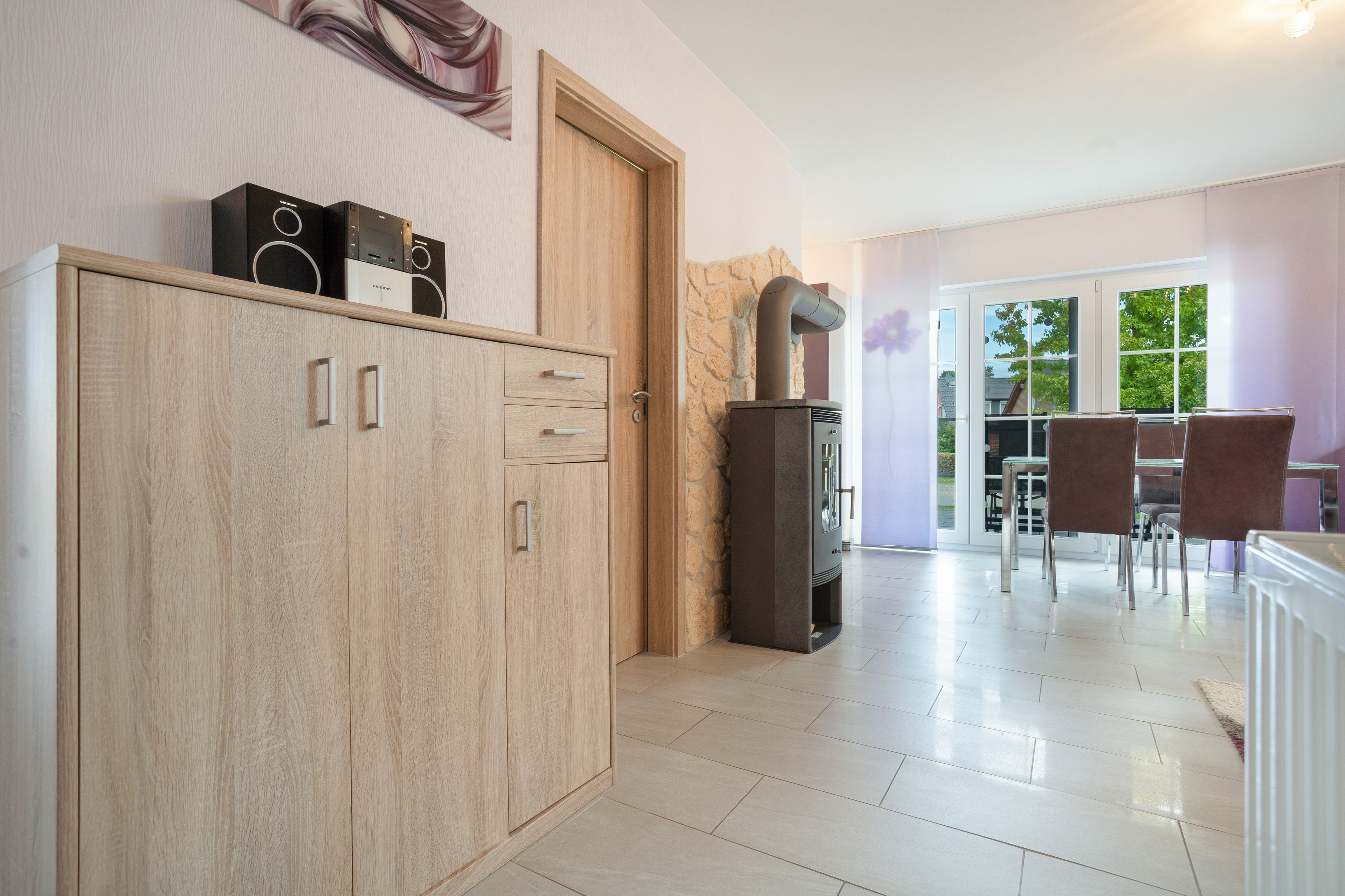 A modern kitchen with wooden cabinets, a built-in stove, and a dining area with a table and chairs.