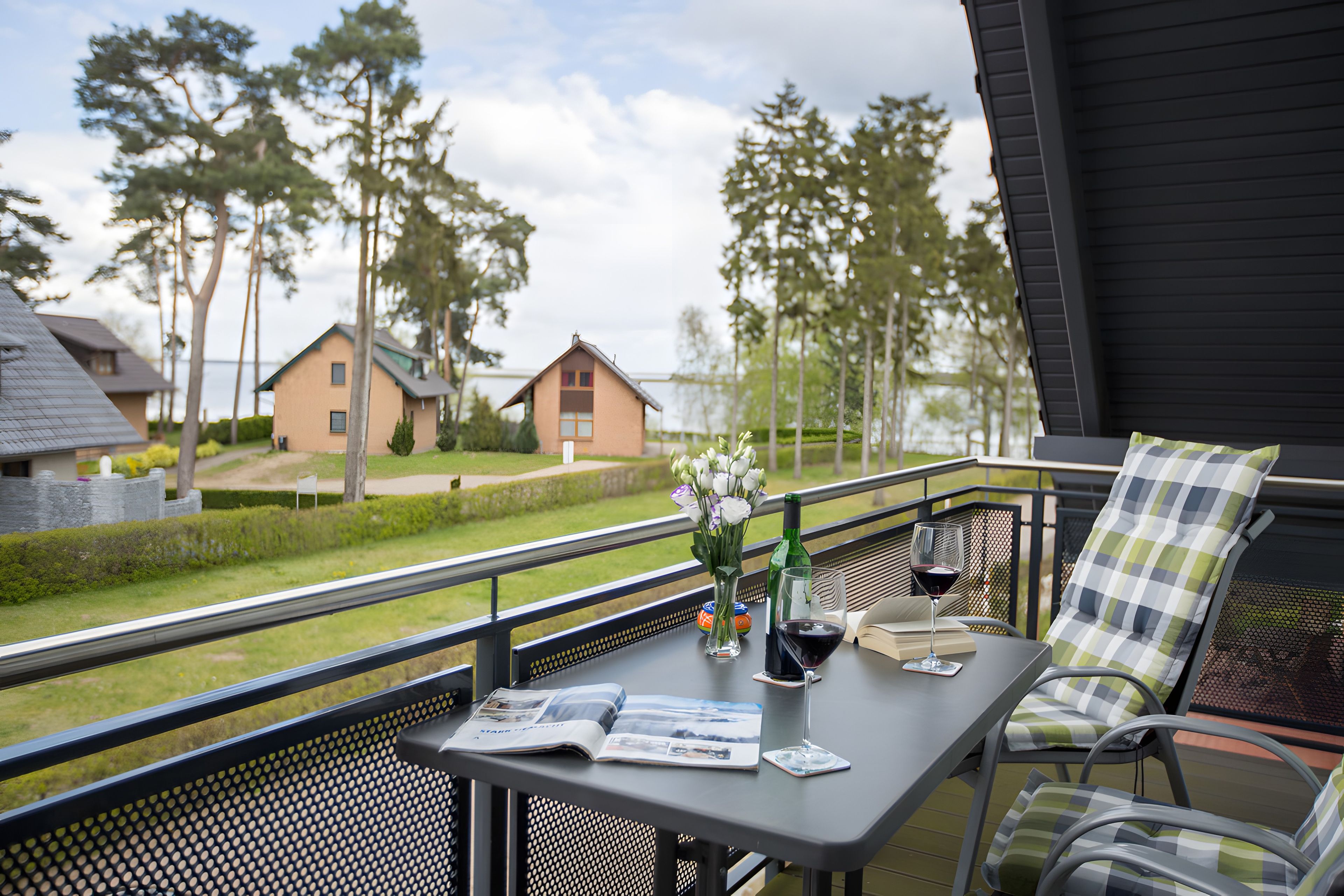 A balcony with a table, a chair, a bottle of wine, and a glass of wine.