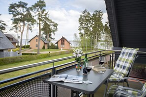 Ein Balkon mit Tisch, Stuhl, einer Weinflasche und einem Weinglas.