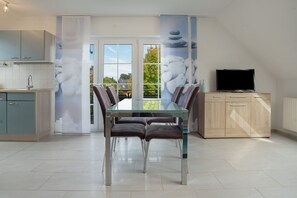 A modern kitchen with a dining area, a TV, and a view through the glass doors. - Apartment 'U 6 OG Biber' with Sea View, Shared Garden and Wi-Fi (Röbel/Müritz)