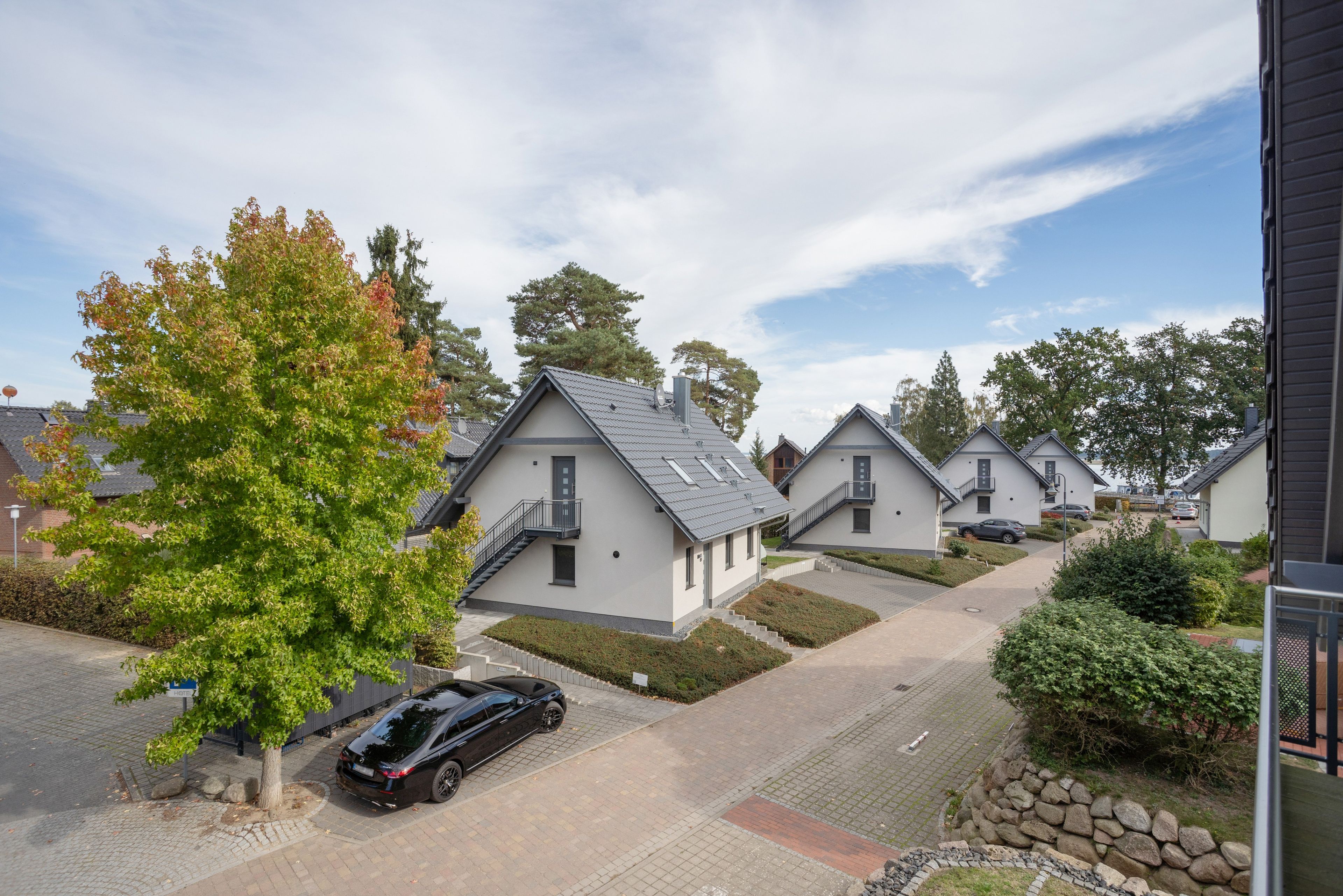 Una zona residencial con casas modernas, un camino de entrada pavimentado y un coche aparcado.