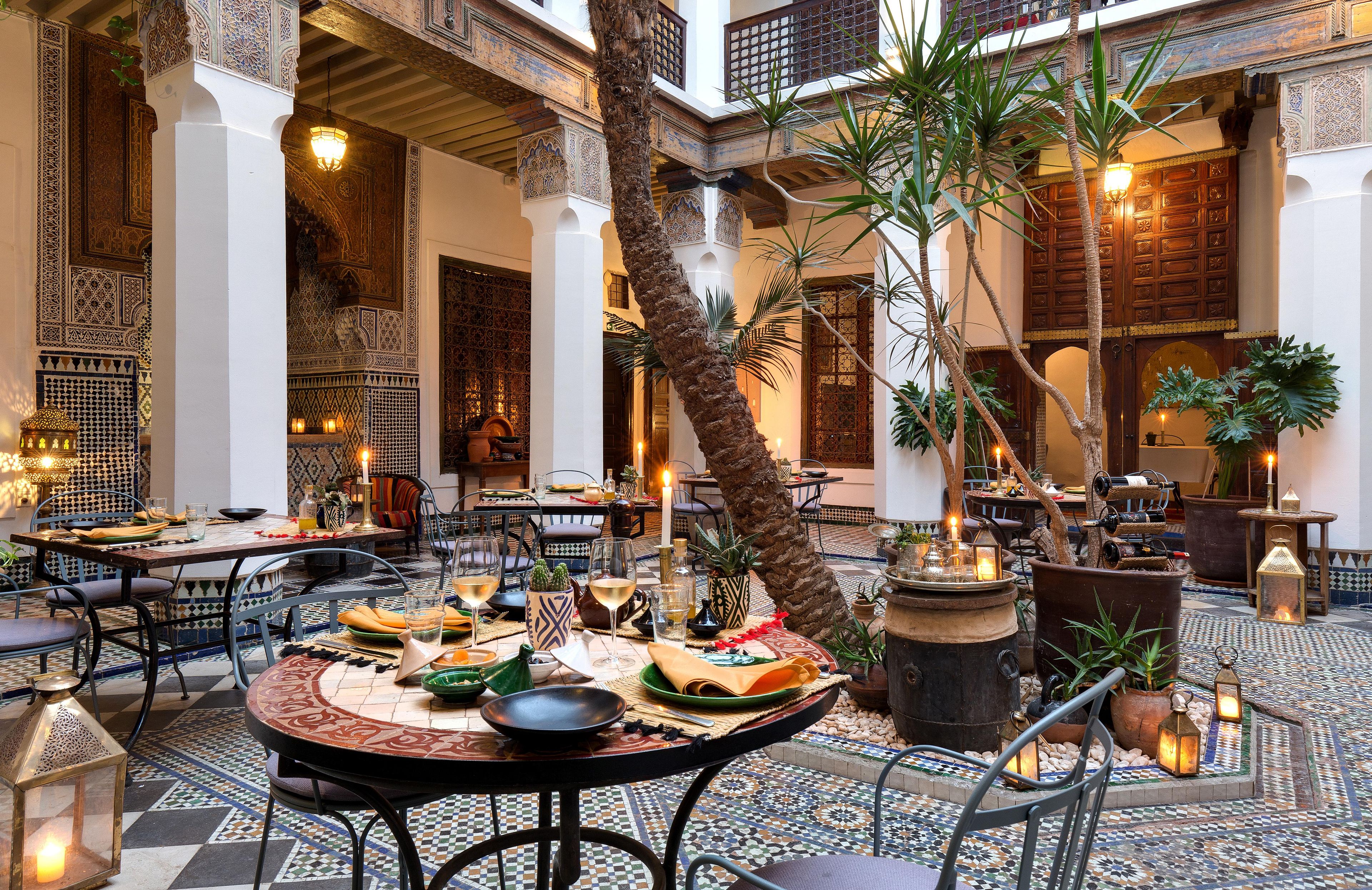 An indoor dining area with tables set for meals, surrounded by ornate walls and columns.