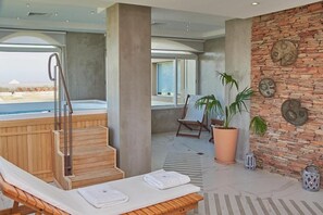 A spa area with a wooden bench, a hot tub, and a stone wall with decorative plates. - Hotel Termas Victoria (Victoria)