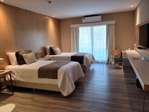 A hotel room with two beds, a desk, a chair, an air conditioning unit, and a large window with curtains. - Hotel Termas Victoria (Victoria)