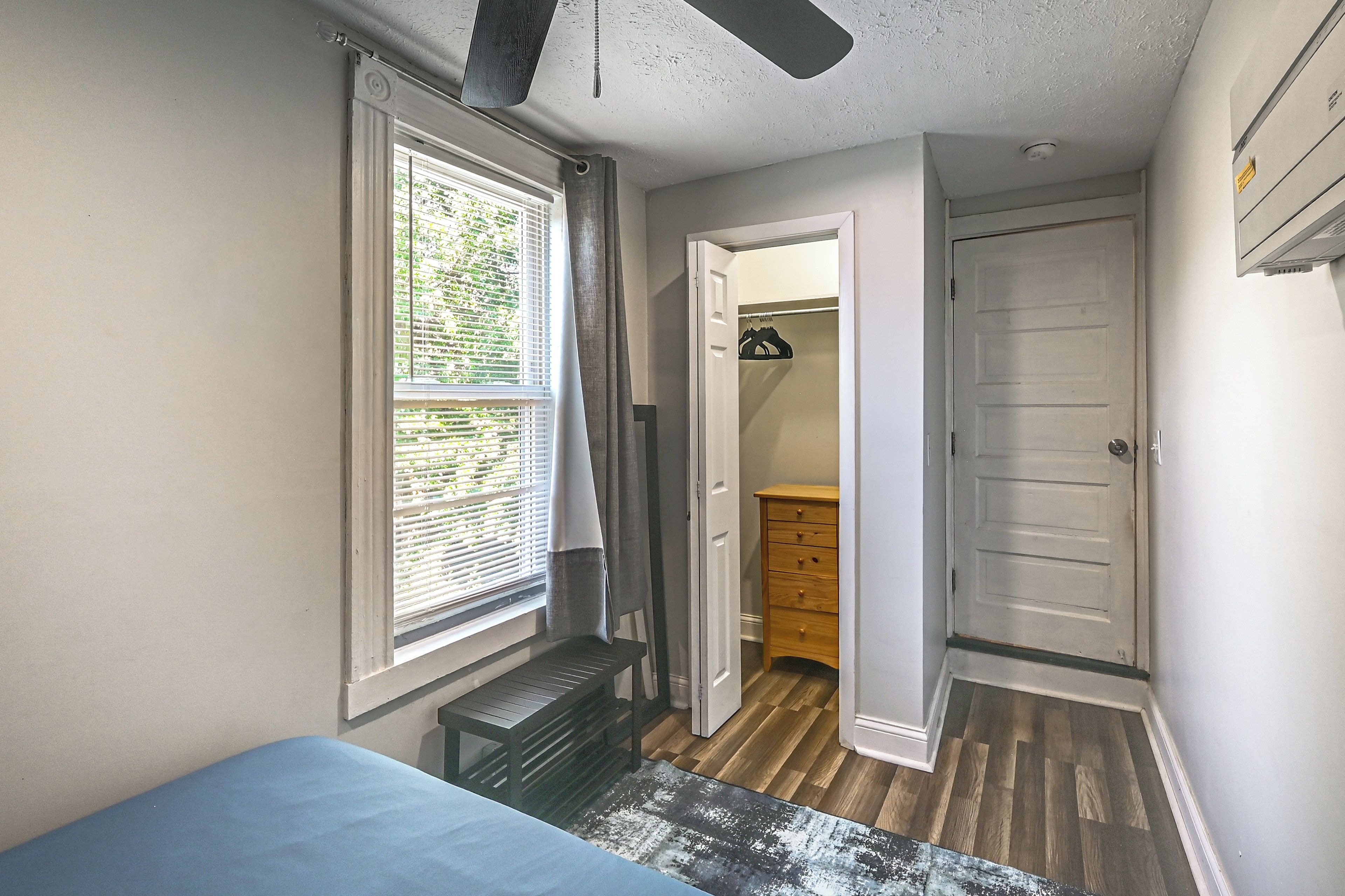 A bedroom with a bed, a window with blinds, a ceiling fan, and a door leading to a closet.