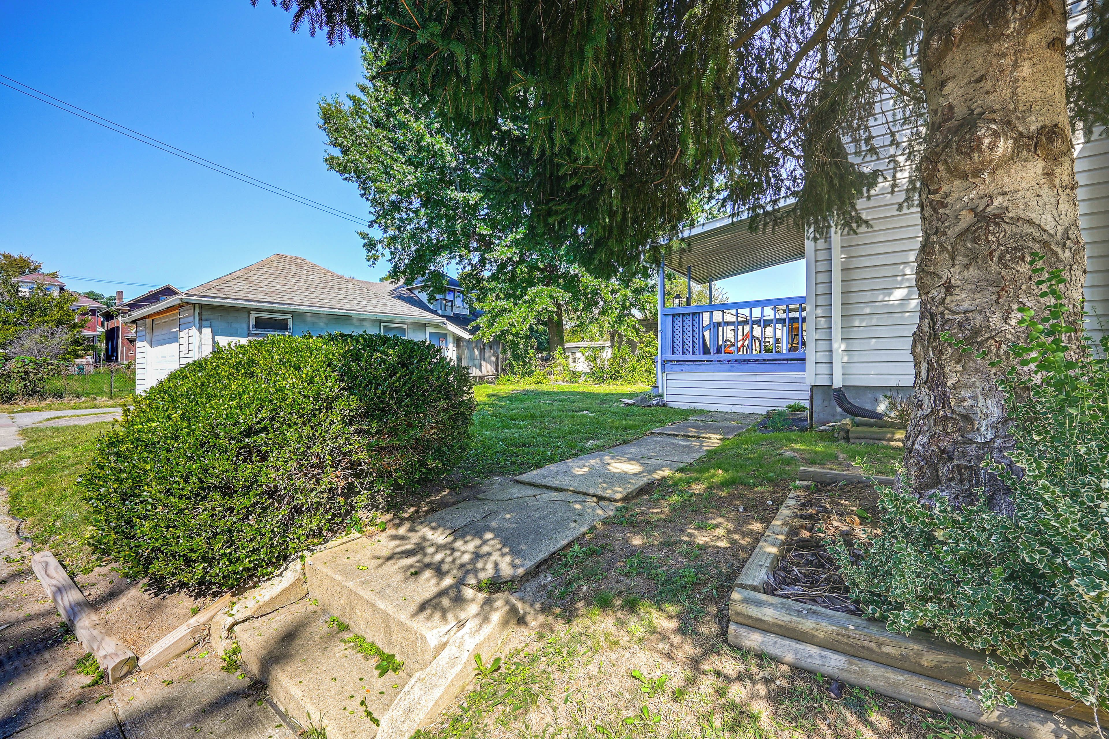A residential property with a paved driveway, a covered porch, and a well-maintained lawn.