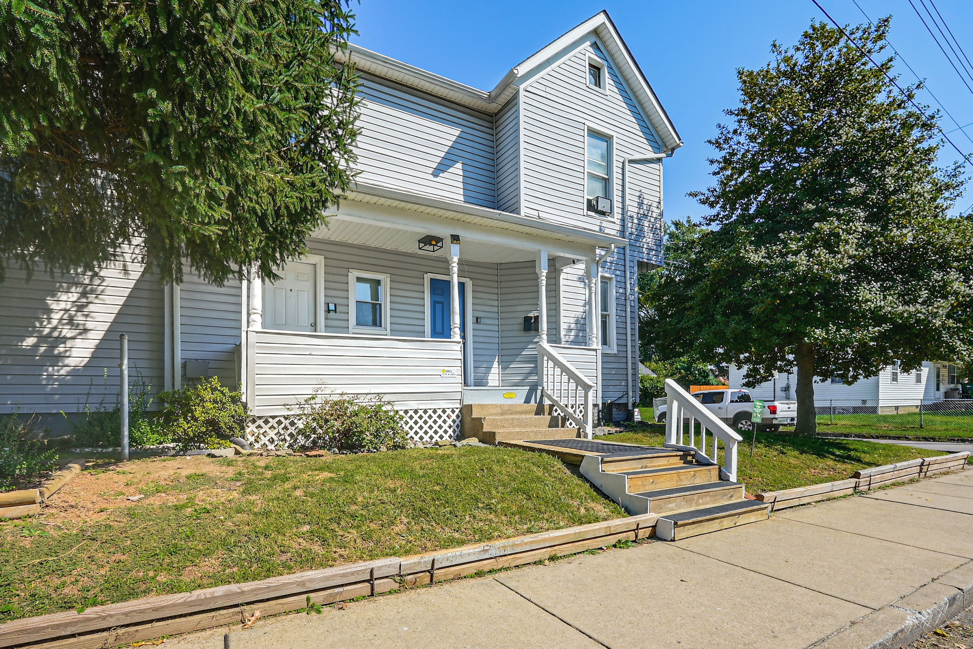 A two-story house with a front porch, a driveway, and a lawn.