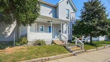 A two-story house with a front porch, a driveway, and a lawn.