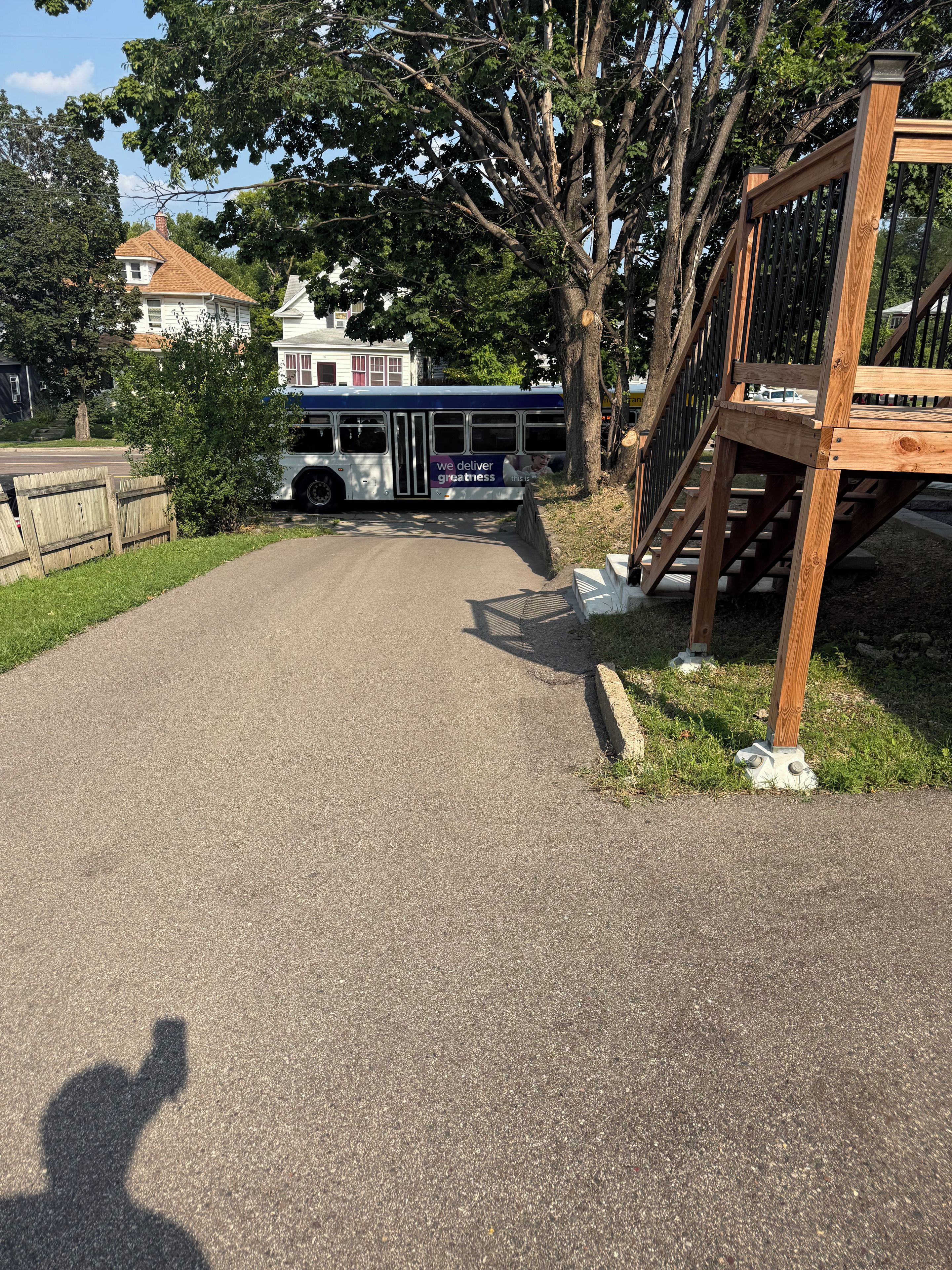 Une route asphaltée menant à un arrêt de bus, avec une clôture en bois et un escalier.