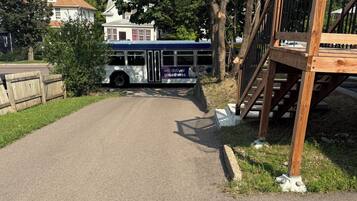 Une route asphaltée menant à un arrêt de bus, avec une clôture en bois et un escalier.