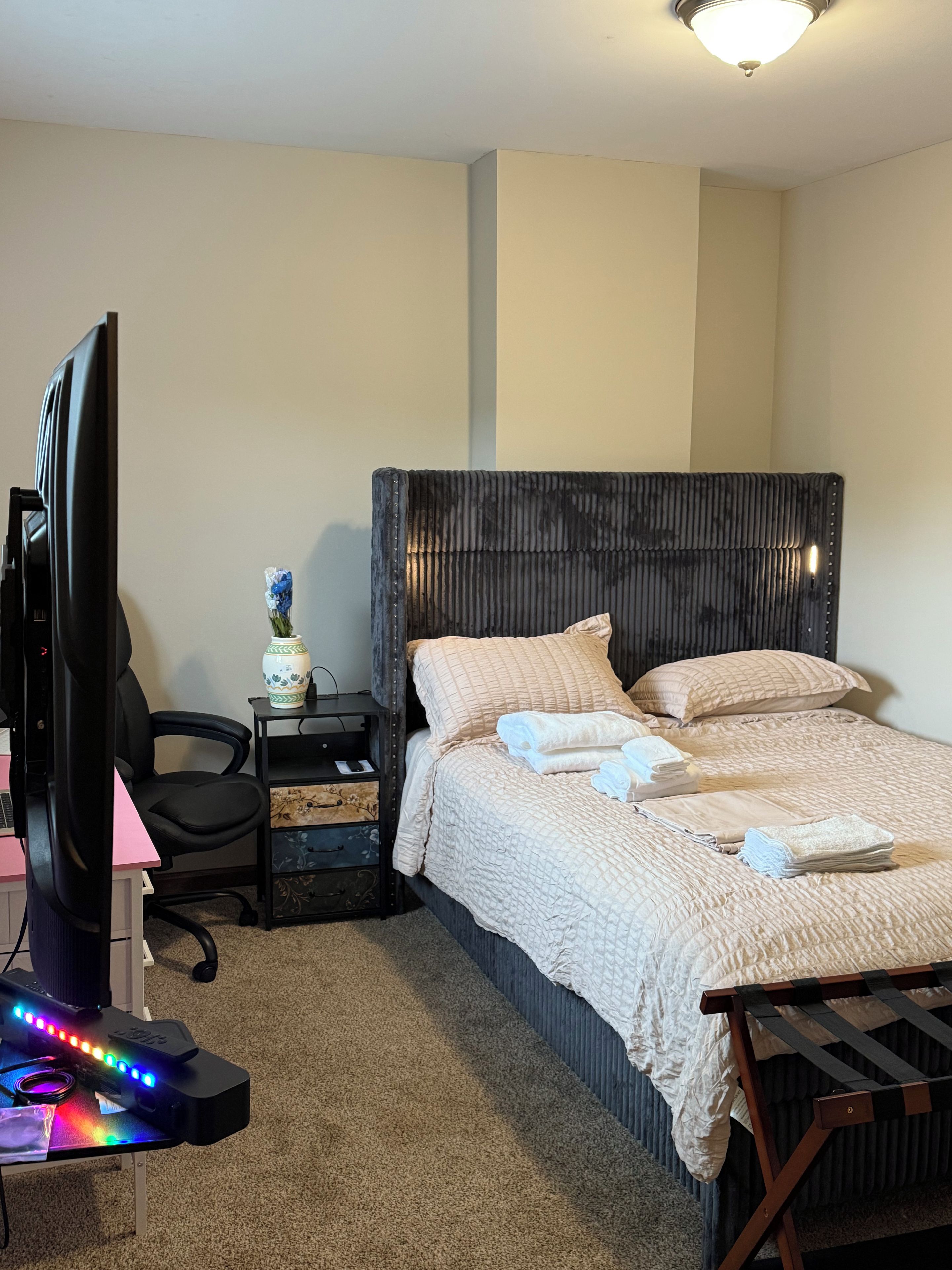 A hotel room with a bed, a desk with a computer, and a chair.