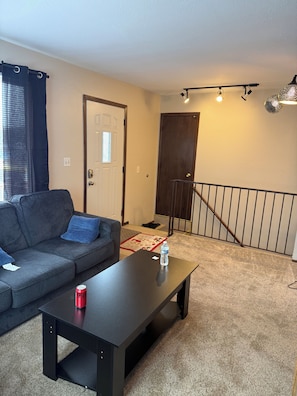 A living room with a sofa, a coffee table, a door, and a staircase. - Charming 2-bedroom Downstairs in fantastic Saint Paul with AC (Saint Paul)
