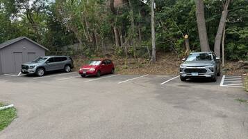 A parking lot with three vehicles, a building, and trees in the background.