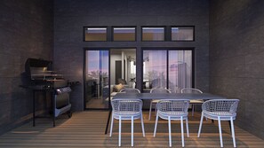Un patio exterior con una parrilla, una mesa y sillas.