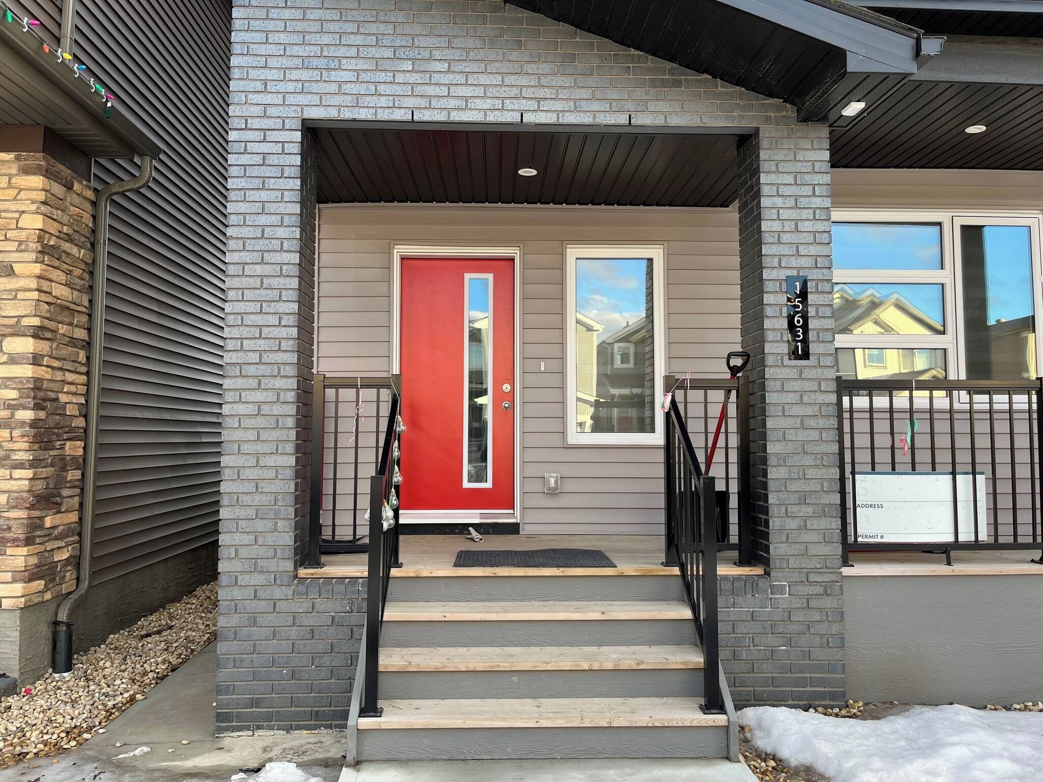 A residential entrance with a red door, a set of stairs, and a mailbox.