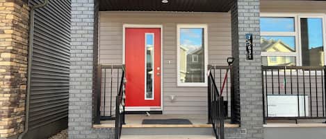 A residential entrance with a red door, a set of stairs, and a mailbox.