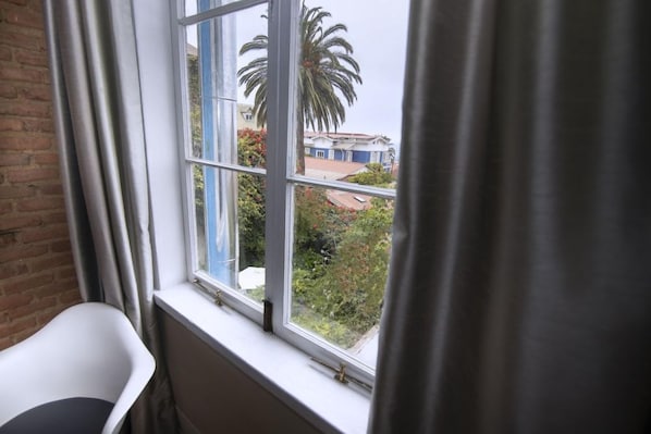A room with a window overlooking a garden and a building. - New Voga Hotel Boutique (Valparaiso)
