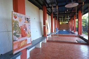 Un espacio al aire libre cubierto con piscina, bancos y una pared decorada con un mural.