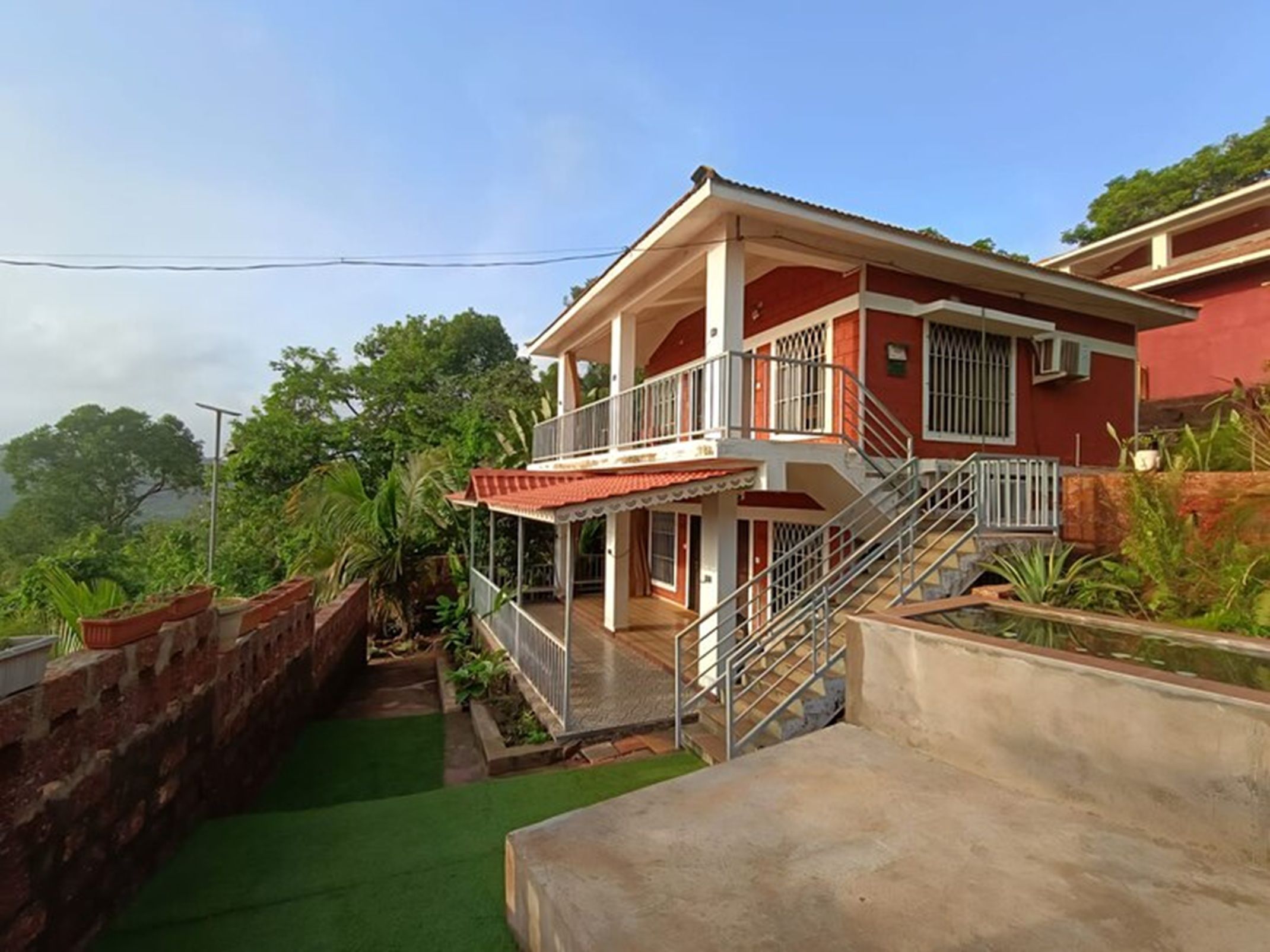 Une maison à deux étages avec un balcon, un escalier et un petit jardin.