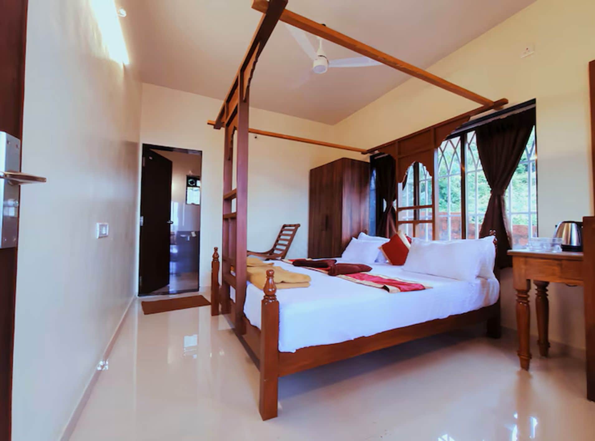 Un dormitorio espacioso con cama con dosel, un armario de madera y un gran ventanal con cortinas.
