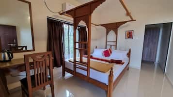 Een kamer met een hemelbed, een bureau met een stoel en een grote spiegel.