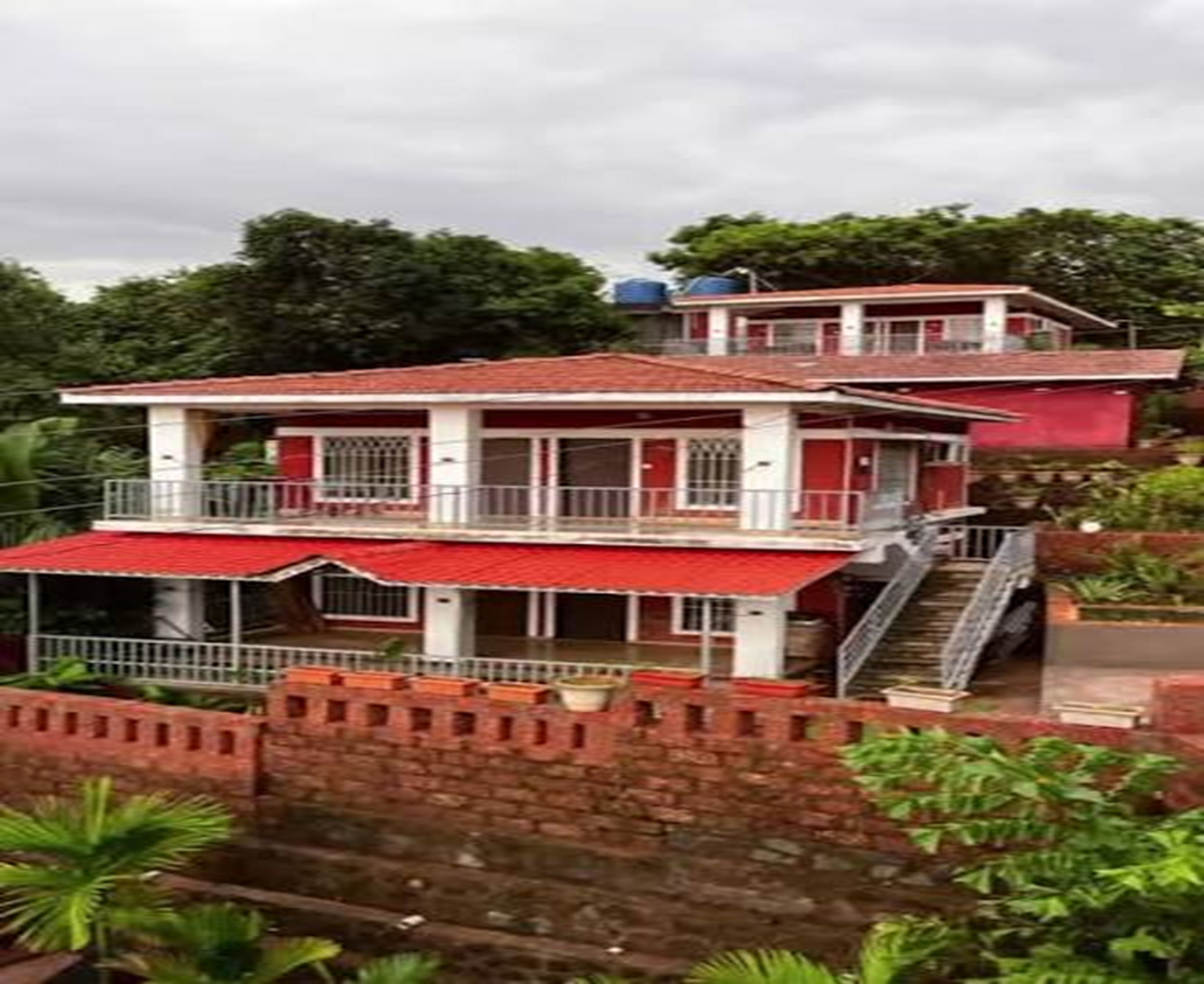 Un edificio de dos pisos con techo rojo y paredes blancas, que cuenta con un balcón en el nivel superior.