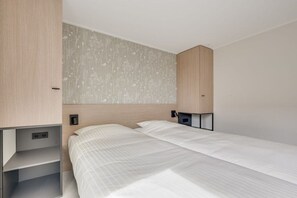 A modern bedroom with a bed, built-in shelving, and a wall-mounted light fixture. - Piet Mondriaanpad 3 West Chapel (Westkapelle)