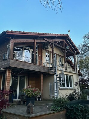 A two-story house with a balcony, a staircase, and a large window. - Perched studio apartment with a terrace overlooking the river—nature and tranquility near Nancy (Pulligny)