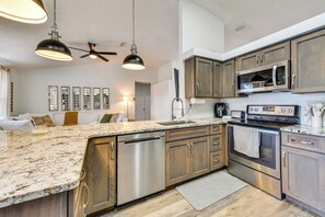 Cozinha moderna com bancadas de granito, eletrodomésticos de aço inoxidável e armários de madeira.