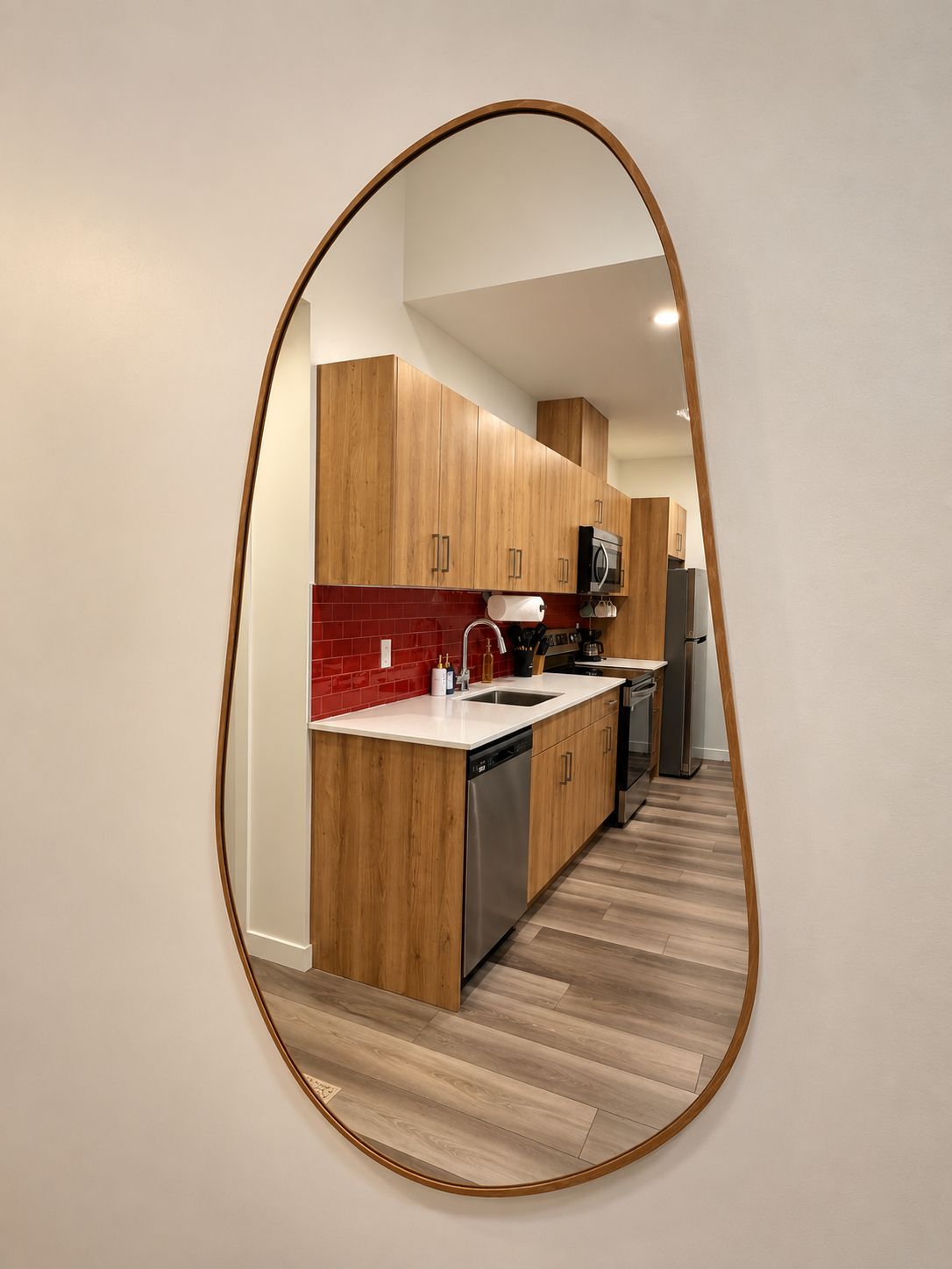 A modern kitchen with wooden cabinets, a red backsplash, and a stainless steel dishwasher.