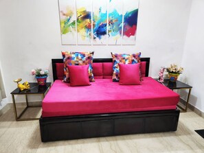 Ein Bett mit einer lebhaften pinkfarbenen Tagesdecke und einem schwarzen Gestell, ergänzt durch zwei passende Kissen.