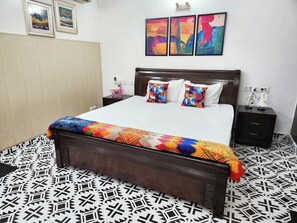 Ein Schlafzimmer mit einem Bett, zwei Nachttischen, einem Holzkopfstück, einem gemusterten Boden und Kunstwerken an der Wand.