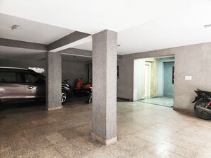 Eine Parkgarage mit einem Auto und einem Motorrad, Betonpfeilern und einem gefliesten Boden.