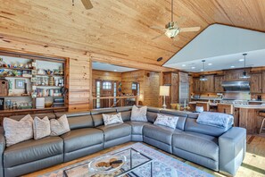 A modern log cabin interior with a sectional sofa, a dining area, and a kitchen. - Pool, Hot Tub & Dock: Lake Hartwell Home (Anderson)