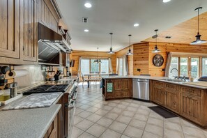 A modern kitchen with wooden cabinetry, a stainless steel stove, and a large island with a sink. - Pool, Hot Tub & Dock: Lake Hartwell Home (Anderson)