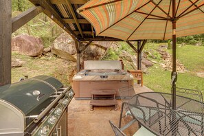 An outdoor barbecue area with a grill, a hot tub, and a table with chairs. - Right on New River! Historic Cabin w/ Hot Tub (Prince)