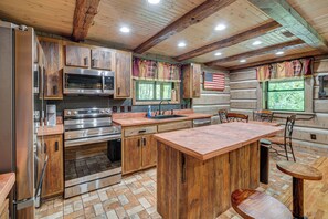 Een landelijke keuken met houten kastjes, roestvrijstalen apparatuur en een centraal keukenblok.