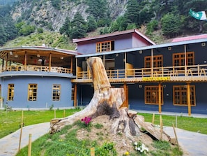 A restaurant with a large tree stump centerpiece, surrounded by a mountainous landscape.