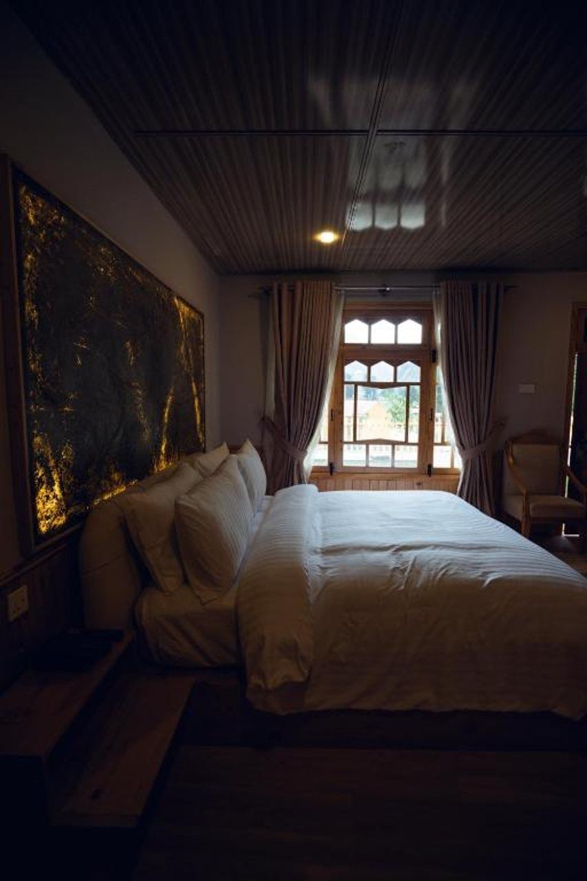 Une chambre avec un grand lit, une fenêtre avec des rideaux et un plafond en bois.