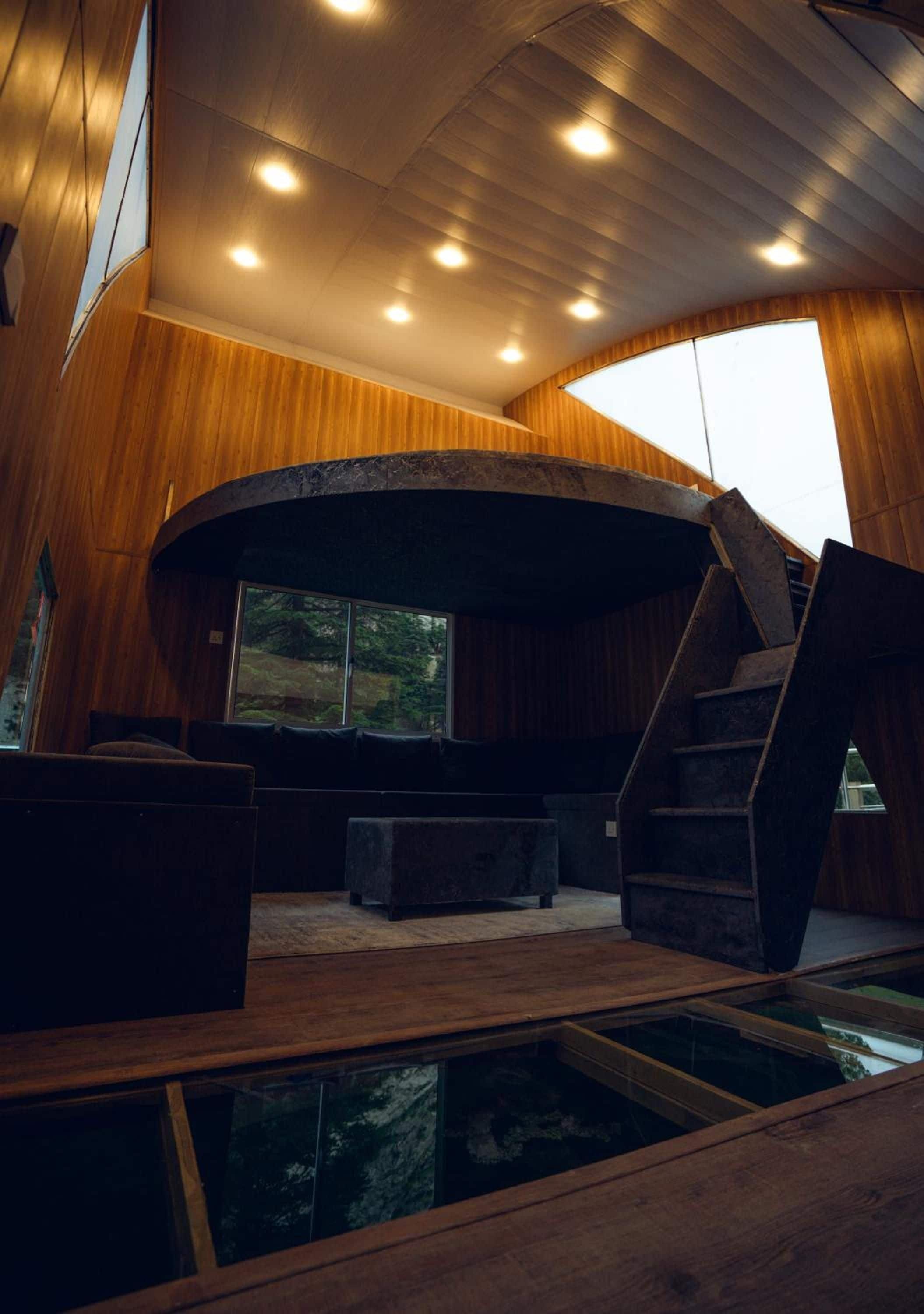 A modern interior with a curved staircase, a seating area, and a view of the outdoors.