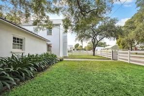 A white house with a well-maintained lawn and a large tree in the front yard. - Pond & Longhorn Views! Timeless Round Top Retreat (Round Top)