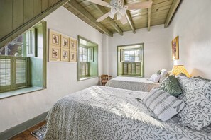 A bedroom with two beds, a ceiling fan, and a window with shutters. - Pond & Longhorn Views! Timeless Round Top Retreat (Round Top)