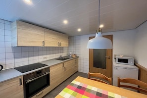 Een kleine keuken met een magnetron, oven en een houten kastje.