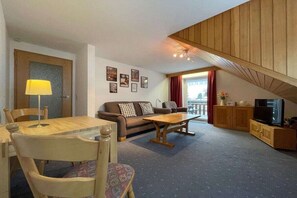 A cozy living room with a sofa, a coffee table, a TV, and a dining area with chairs and a table. - Holiday apartment with 2 bedrooms (Todtnauberg)