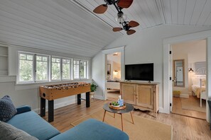 A cozy living room with a foosball table, a television, and a ceiling fan. - 4BR Tampa Home, Easy Access to Dtwn (Tampa)