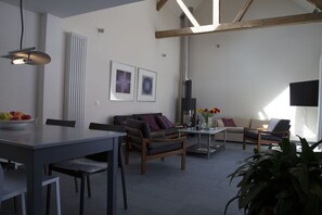 Ein modernes Wohnzimmer mit Essbereich, Kamin und Flachbildfernseher.