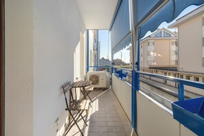 A balcony with a table and chairs, a window overlooking buildings, and a blue awning. - Cuddly House - 2 Terrazzi, Parking, pet Friendly (Cividale del Friuli)